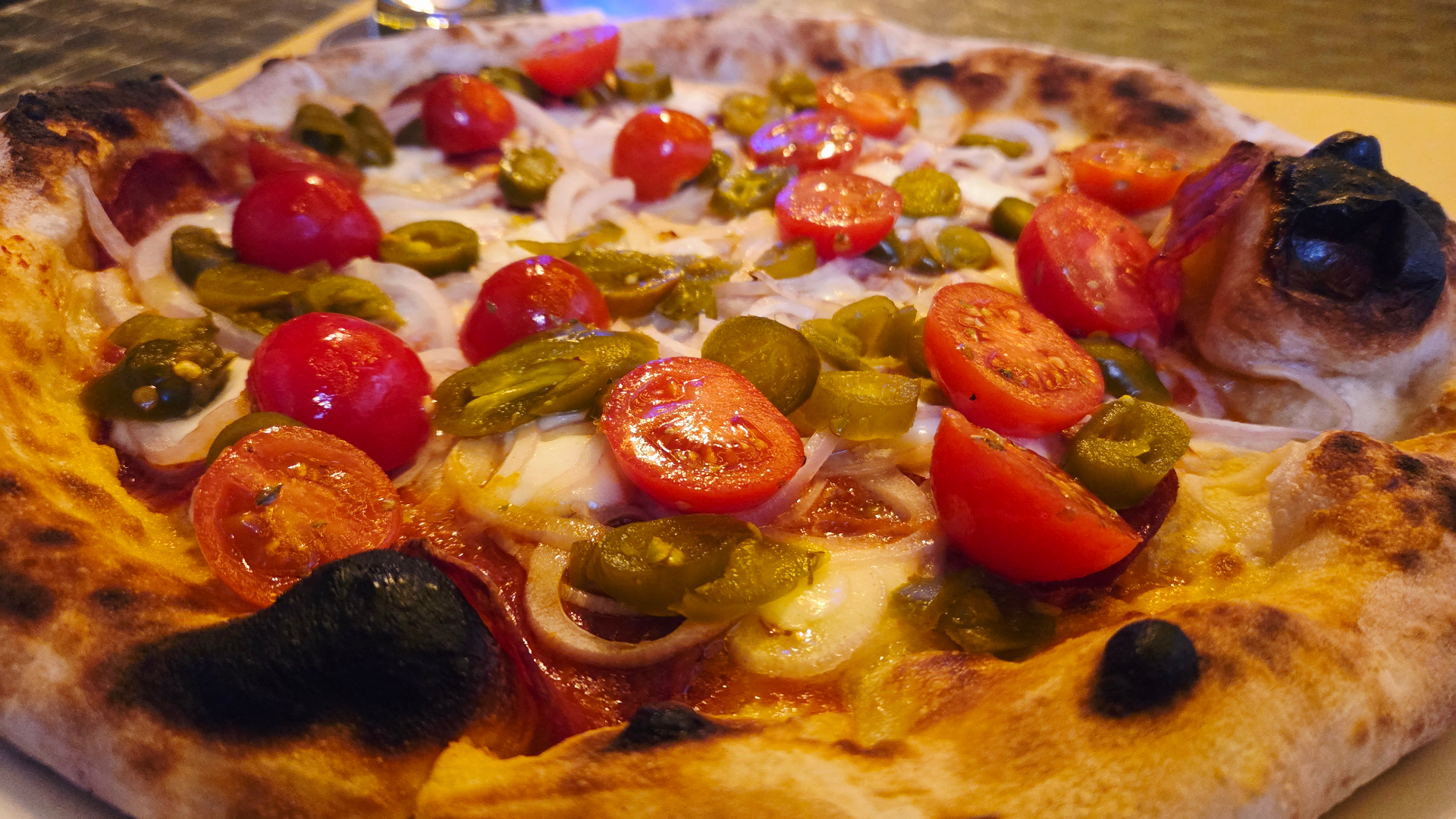 Pizza con pomodorini, jalapeños e cipolla appena sfornata da Rosso 17